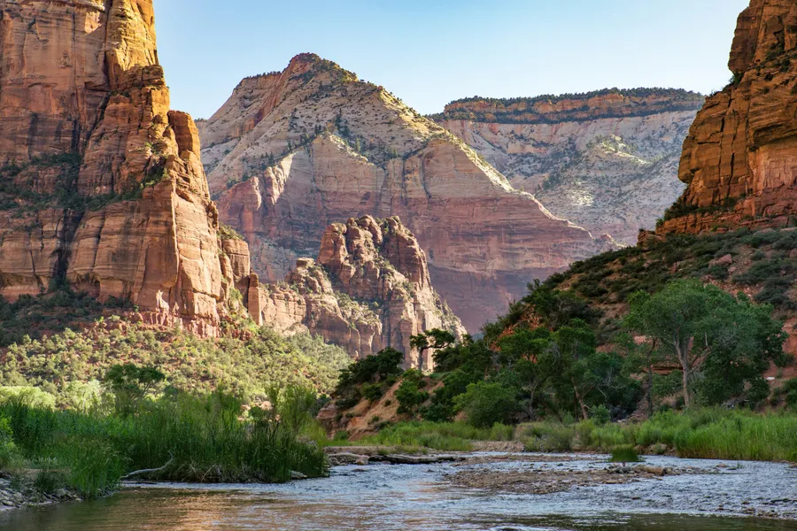 Sunlit red-rock canyon with a river winding through desert greenery
